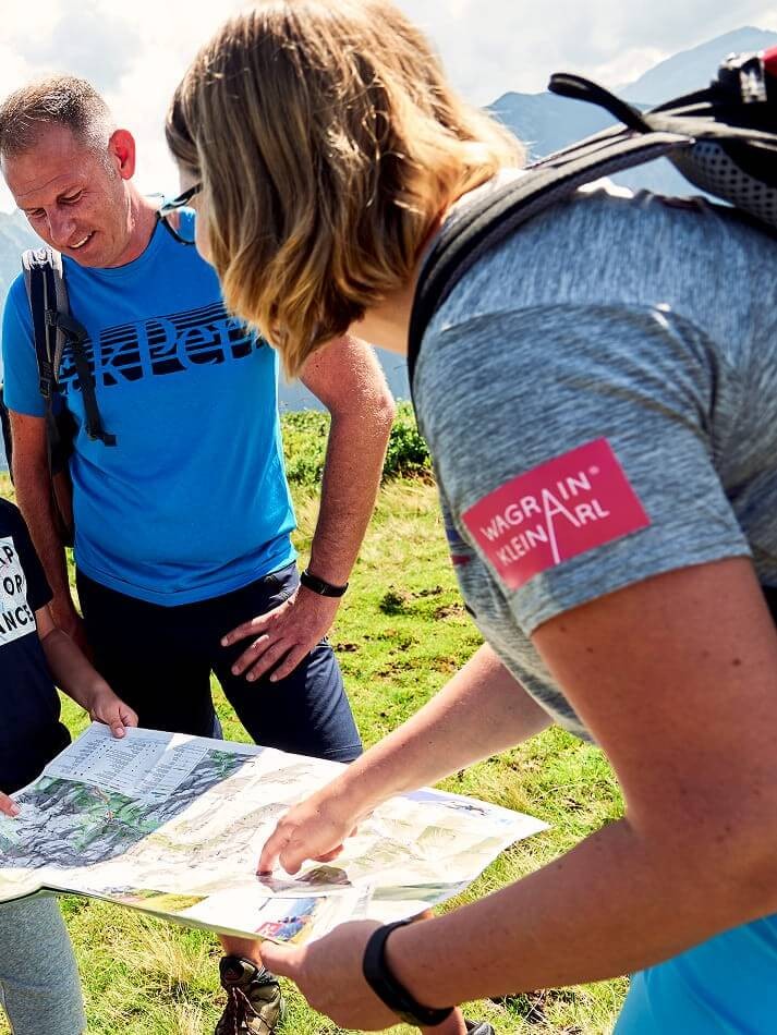 Wandergruppe plant mit Karte ihre Tour in den Bergen von Wagrain-Kleinarl