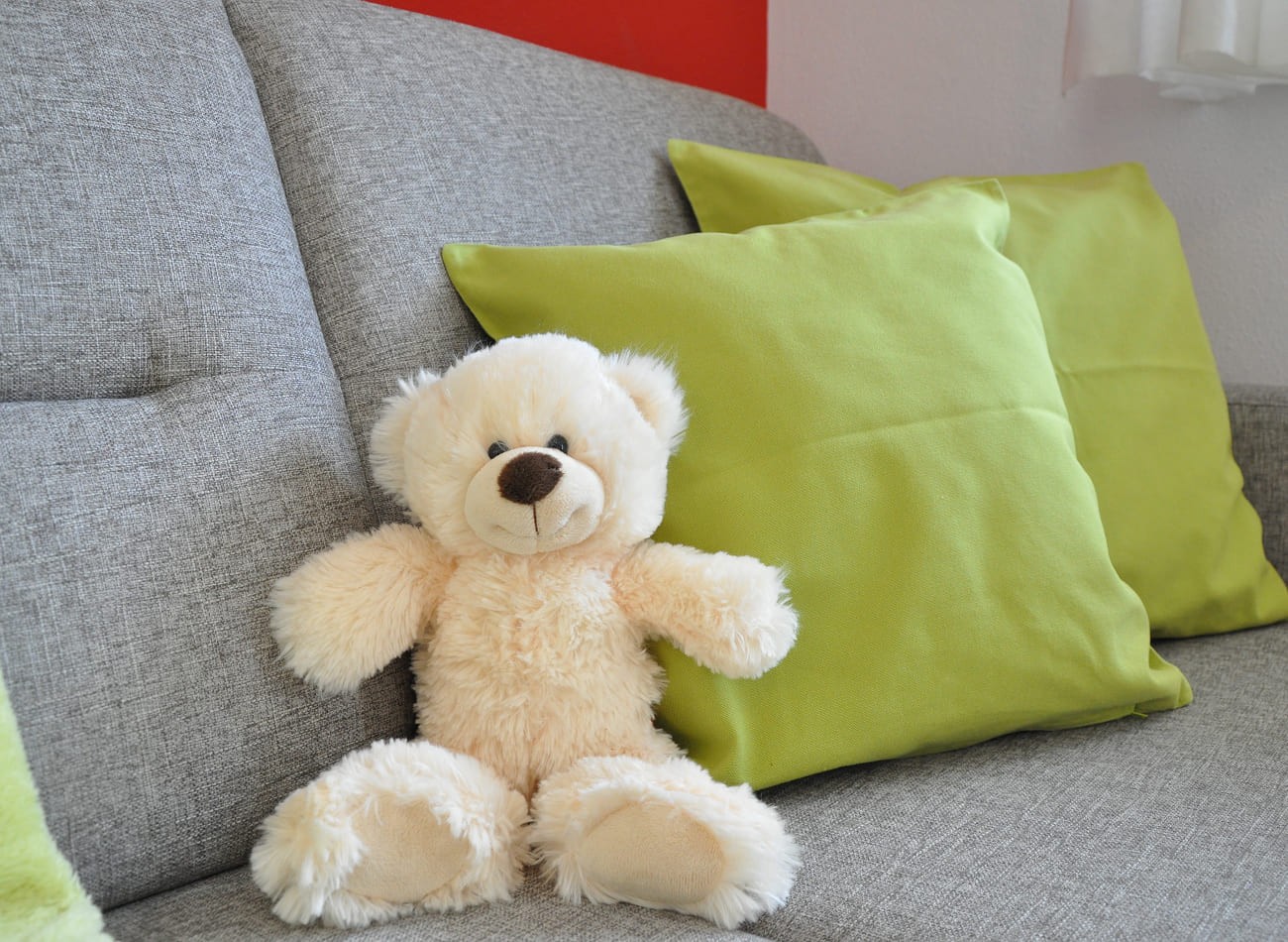 Sofa mit Teddyb&auml;r im Wohnbereich des familienfreundlichen Classic Appartements E1